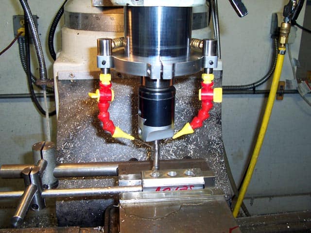 Metalworking machine with a cylindrical body and black, red, and yellow components on a metal workbench.
