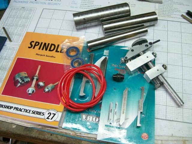 Metalworking tools and materials, including spindle operation guide, on a grid-lined surface.