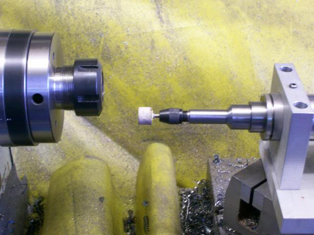 Metalworking lathe with tools and machinery in background.