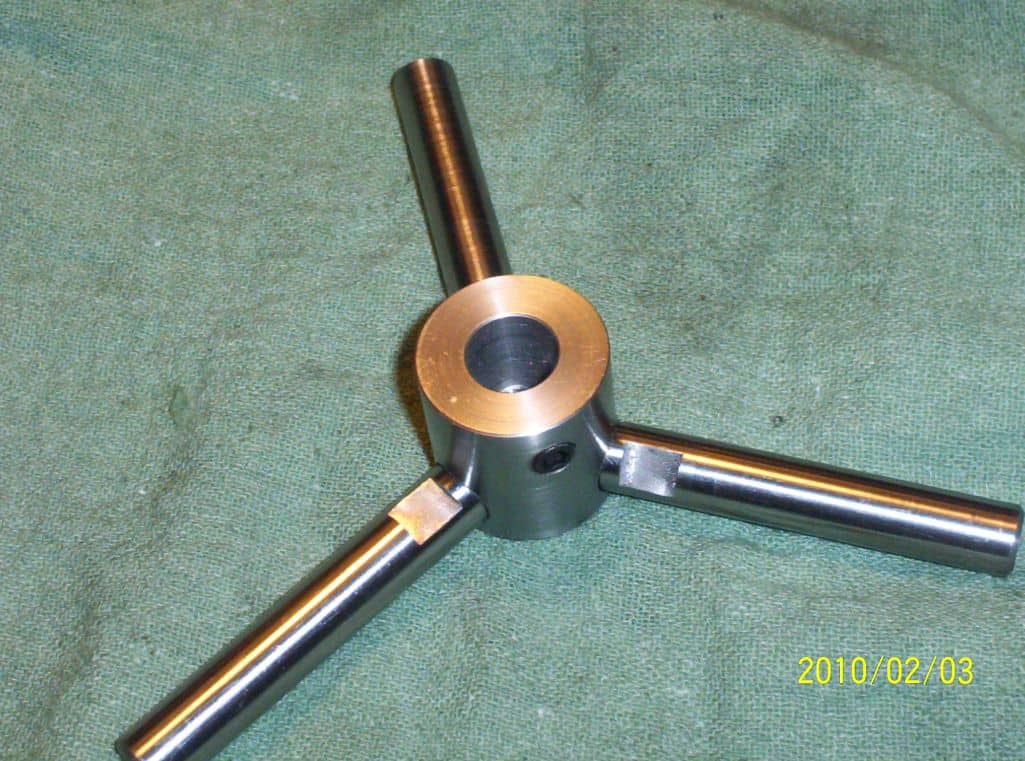 Silver metal tripod tool on green cloth.