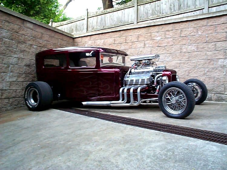 Vintage-style hot rod car with a deep red finish and chrome accents.