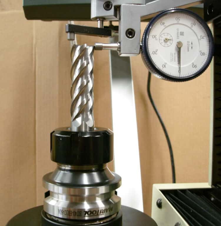 Precision instrument with silver spiral-shaped object on black base and gauge with white dial.