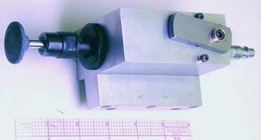 Metal component with black knob and small hole above grid pattern.