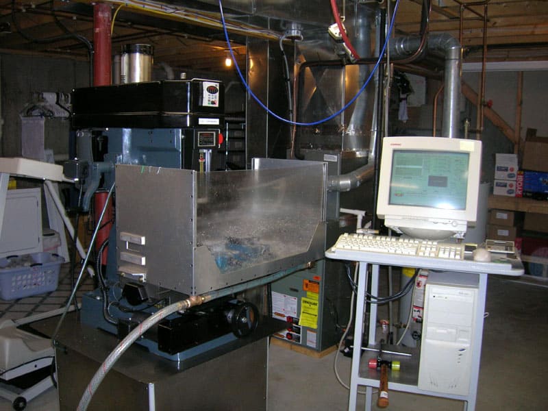 Industrial machining equipment with pipes, wires, and control panels, accompanied by a computer monitor.