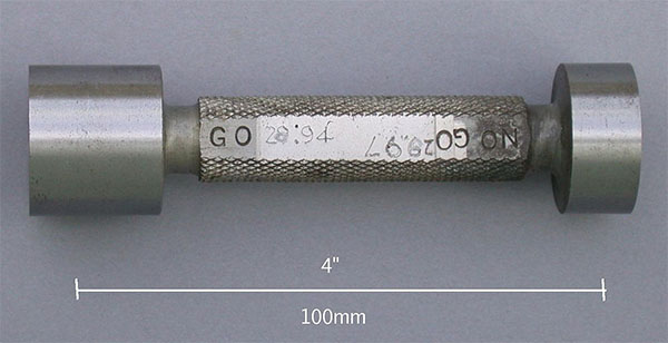 Precision measuring tool with cylindrical body, threaded top and flat bottom ends, featuring a scale reading "GO 0-94" and additional markings on a 4-inch long knurled surface.