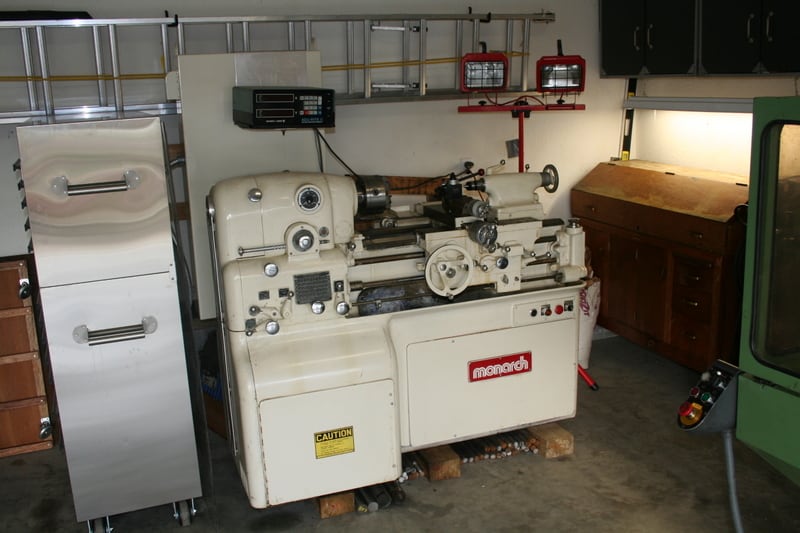 Well-organized home workshop with tools and equipment, including refrigerator, lathe, and workbench.