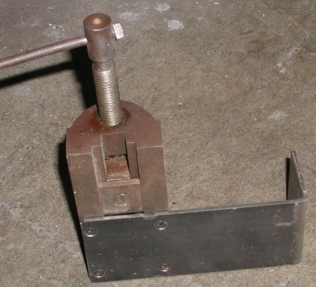 Rusty metal machinery on a concrete floor, handle to left, worn and weathered body.