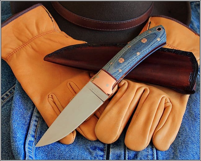 Close-up of a pocket knife on work gloves and jeans.