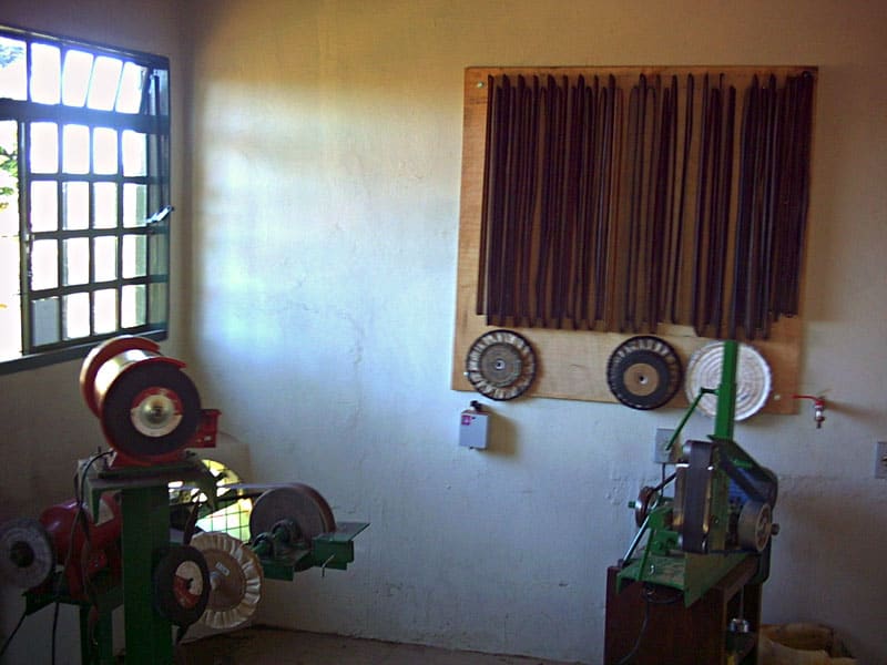 A workshop with a knife grinder and vertically arranged metal rods on a white-painted wall.