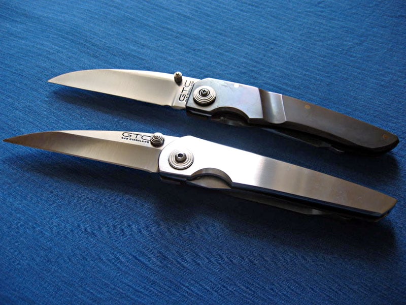 Two pocket knives with curved blades on a blue background.
