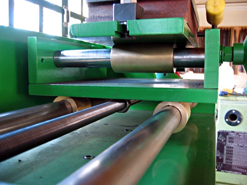 Green metalworking machine with cylindrical surface grinder and various tools in a workshop background.