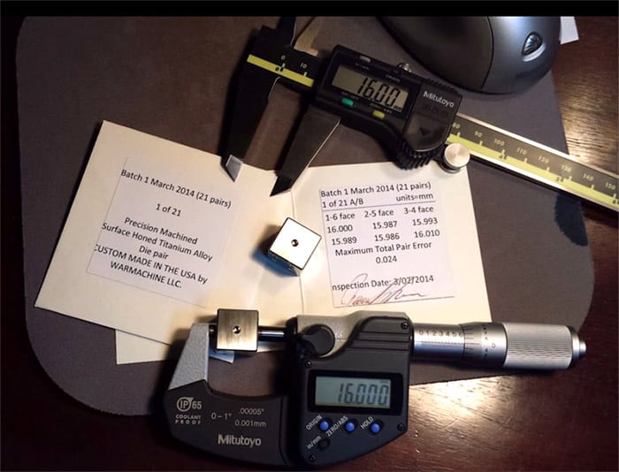 Precision measuring tools: micrometer, calipers, and white die with black dots on a dark background.