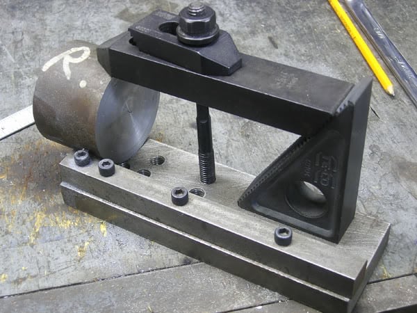 Metalworking tool on a workbench, cylindrical body with flat base and rounded top.