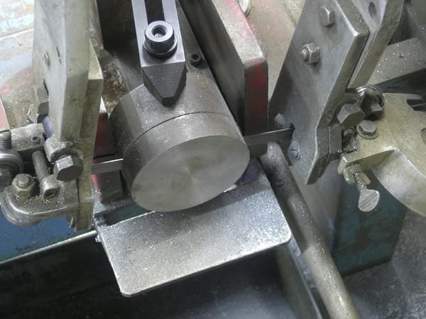 Industrial machinery with cylindrical metal part and surrounding mechanical components.