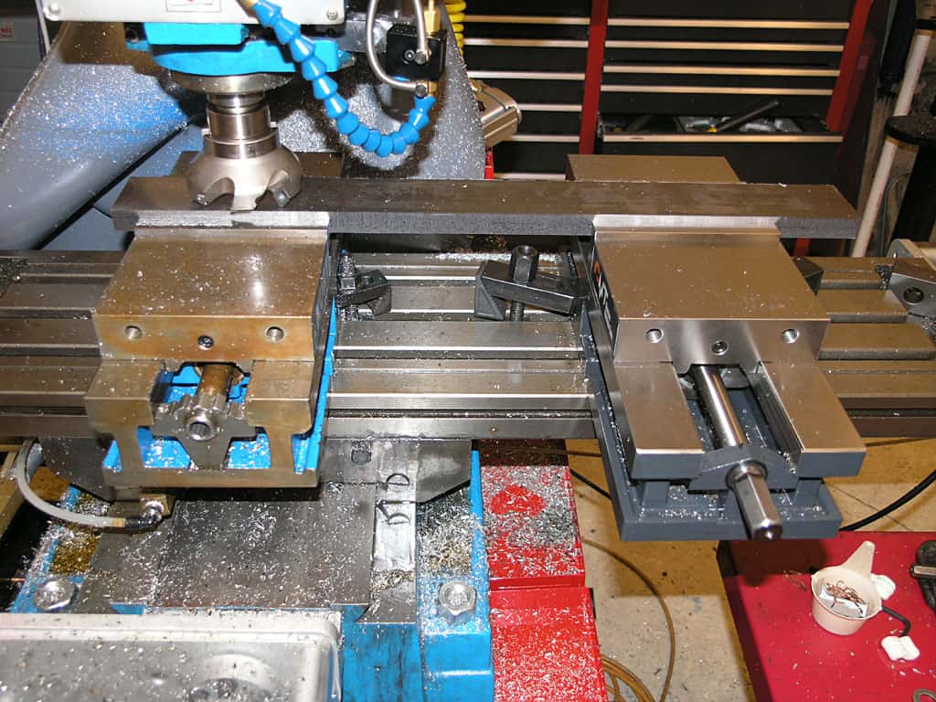 Milling machine in workshop or factory setting with blue and red base.