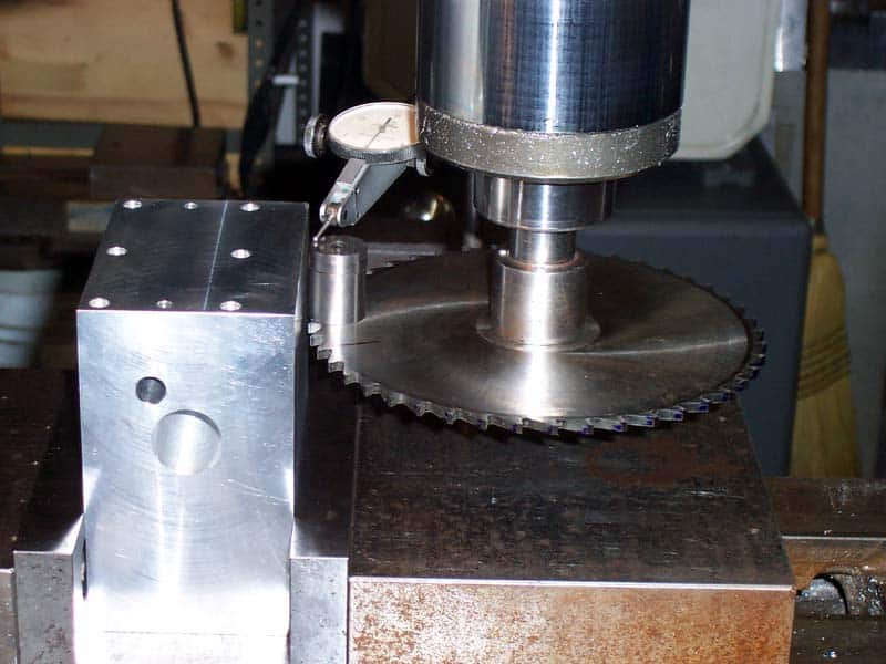 A circular saw blade mounted on a metal base with a cylindrical attachment.
