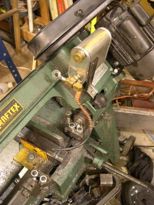 Green metal bandsaw with yellow lettering and silver cylinder, in a workshop setting.