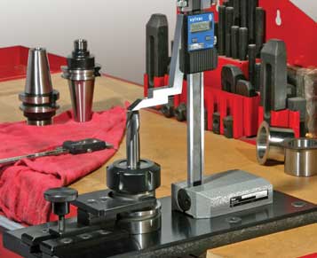 Height gauge on metal stand in workshop or machine shop.