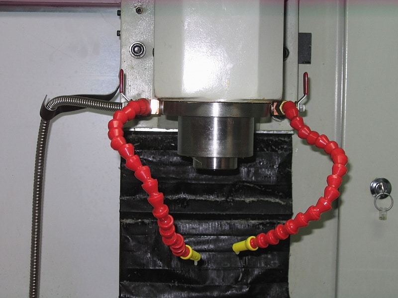 Metal manifold with two red plastic hoses attached.