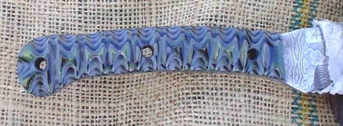 Blue and white patterned blade with serrated edge on light-colored fabric background.