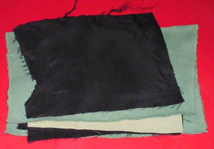 Torn gray and black cotton fabric on a red background.