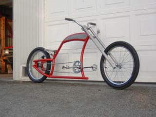 Custom motorcycle with red frame, black tires, and chrome accents.