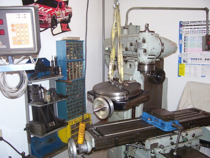 Industrial lathe in a workshop setting, surrounded by various tools and equipment.
