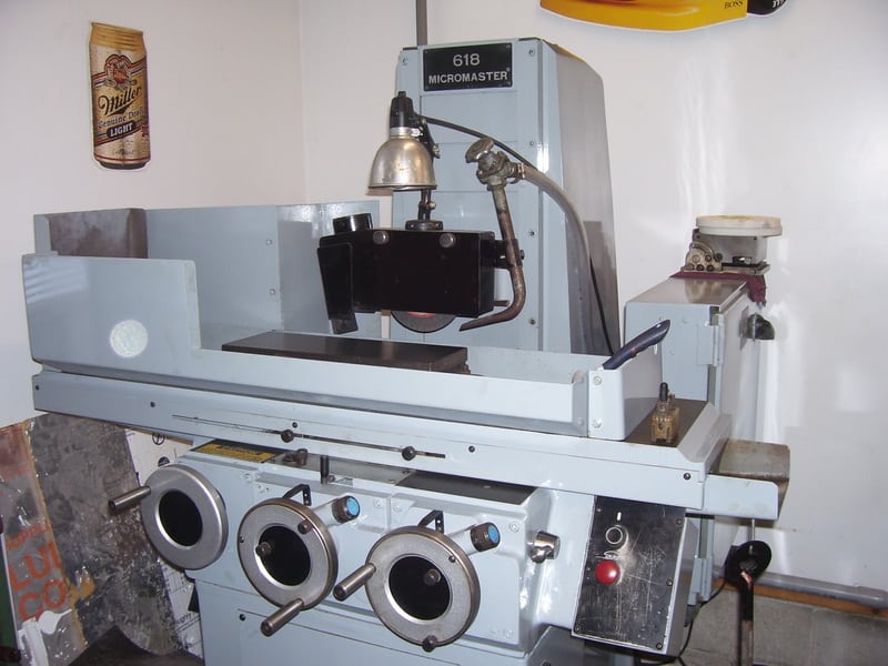 A large white machine with black accents and dials sits in a workshop or factory.