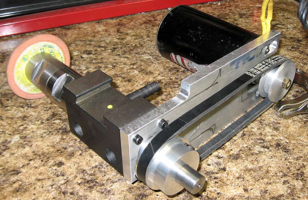 Silver metal device with black base, two cylindrical protrusions, and small yellow dot.