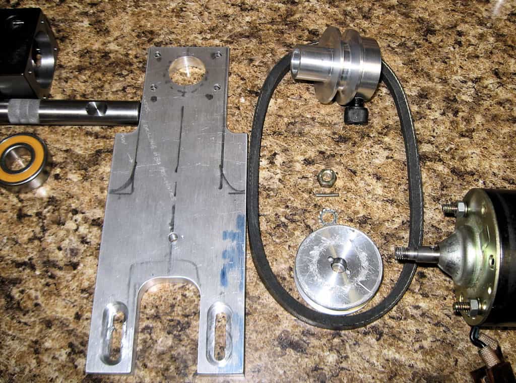 Metal parts, including gears and bearings, on a granite countertop.