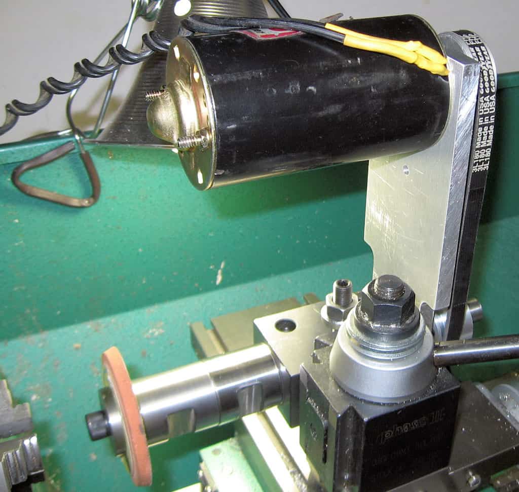 Black cylindrical object with yellow cord, on green metal surface.