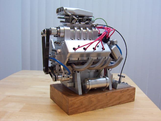 Engine block on wooden base with wires.