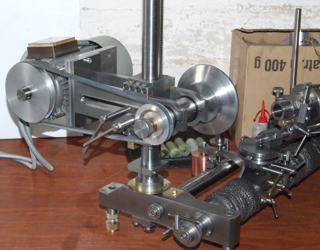 Large metal machine with gears, pulleys, and levers on a dark wooden table.