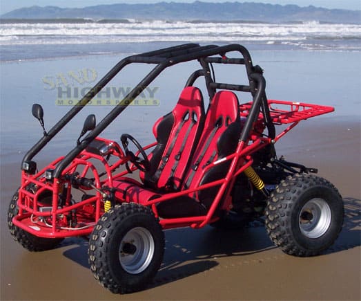 Red dune buggy on sandy beach with black trim, four wheels and roll cage.