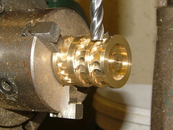 Metalworking lathe with rotating spindle and drill bit in use.