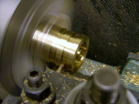 Brass component being machined on a lathe.