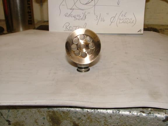 A metal object with a circular base, small holes in the center, on top of handwritten notes.