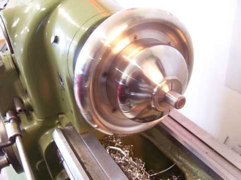 Large green lathe with shiny silver 5C chuck in sharp focus.