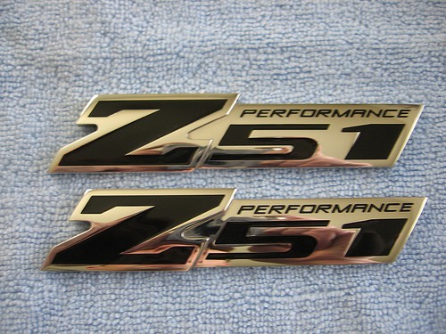 Two shiny gold Z51 Performance logos on a textured surface.