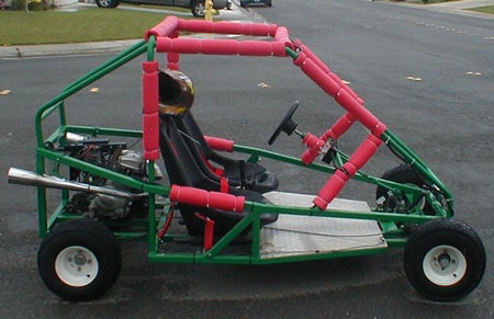 Green and red go-kart or dune buggy with roll cage.