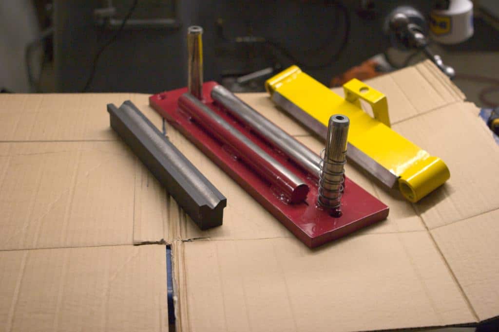Metalworking tools and parts on cardboard box in workshop setting.