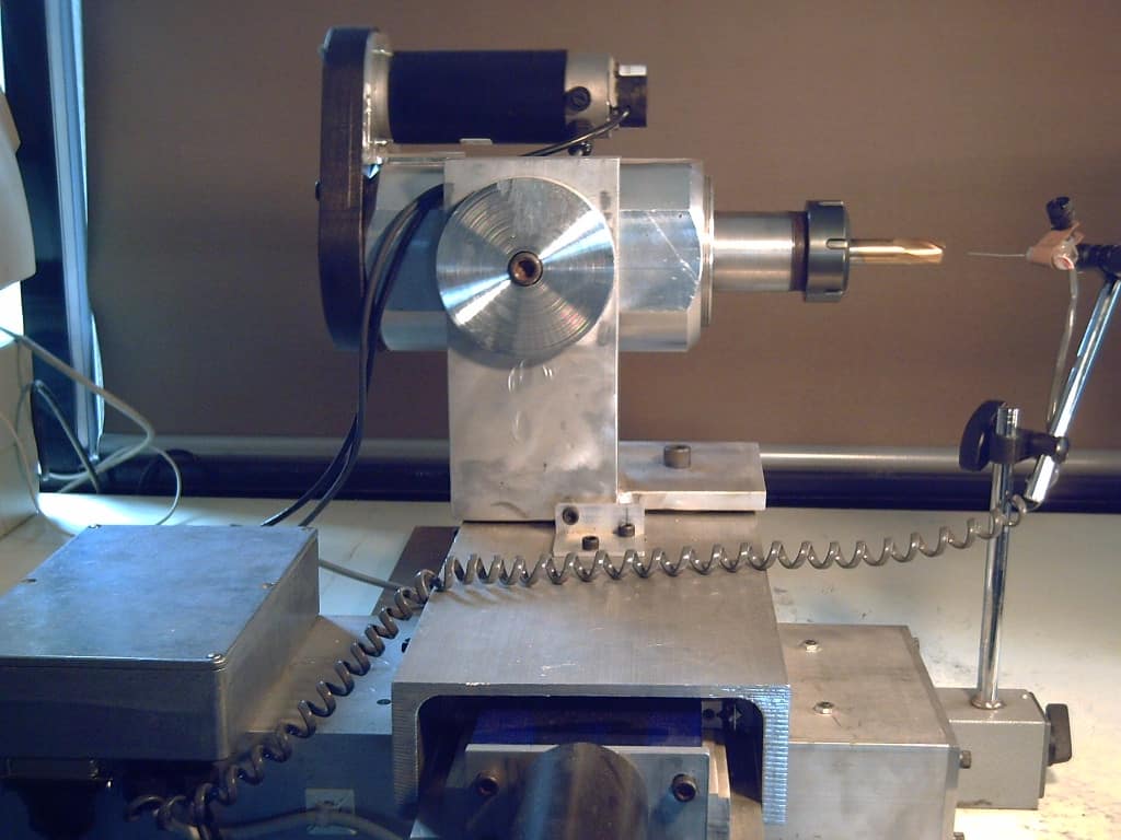 Silver metal device with cylindrical shape and spiral spring on a white tabletop.