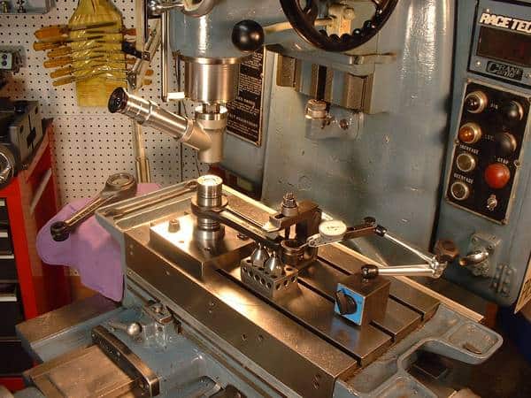 Large metalworking drill press with rotating spindle and table.