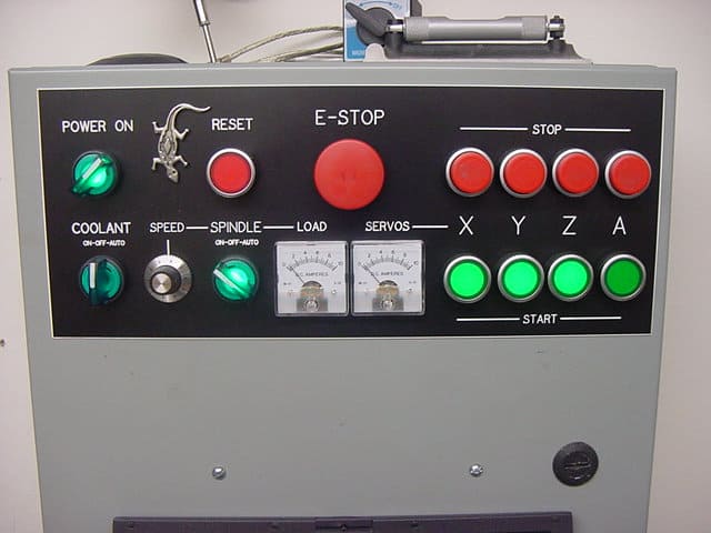Manufacturing control panel with red and green buttons, knobs, and dials.