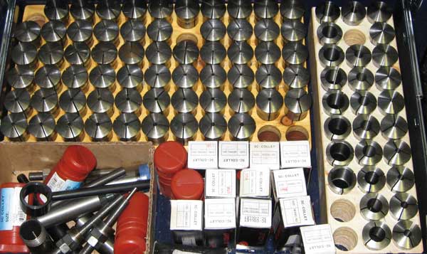 Metal objects arranged on light-colored background: conical black metal, red plastic/metal, and white boxes.