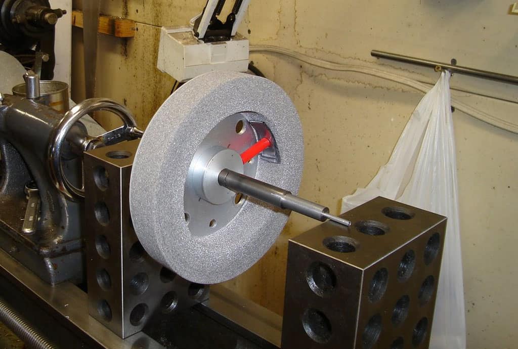 A large grinding wheel mounted on a metal lathe.