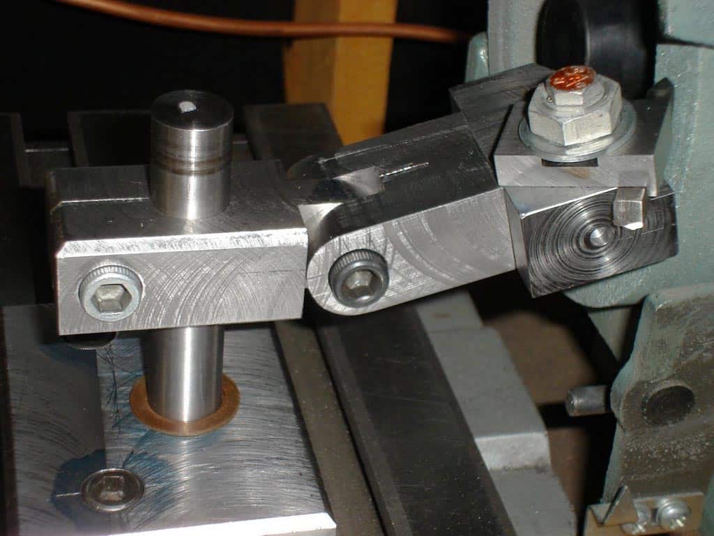 Metal component with cylindrical protrusion and T-shaped arm on a workbench or machine table.