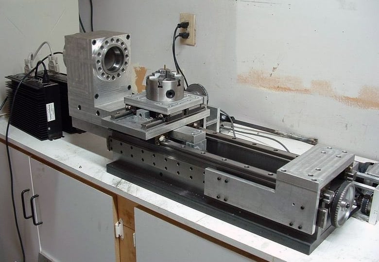 Home-built CNC lathe in a workshop setting, with metal frame, precision components, and control panels.