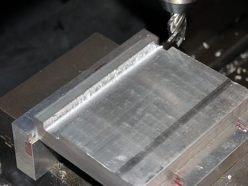 Metal milling process, partially machined aluminum block, rough edges, first chips.