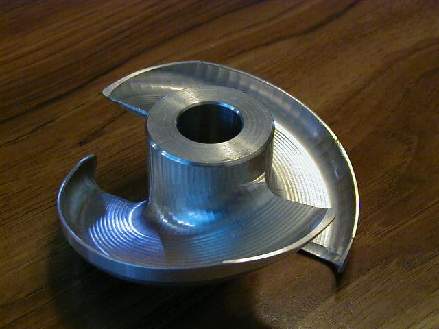 Silver metal impeller with curved fins and central hole.